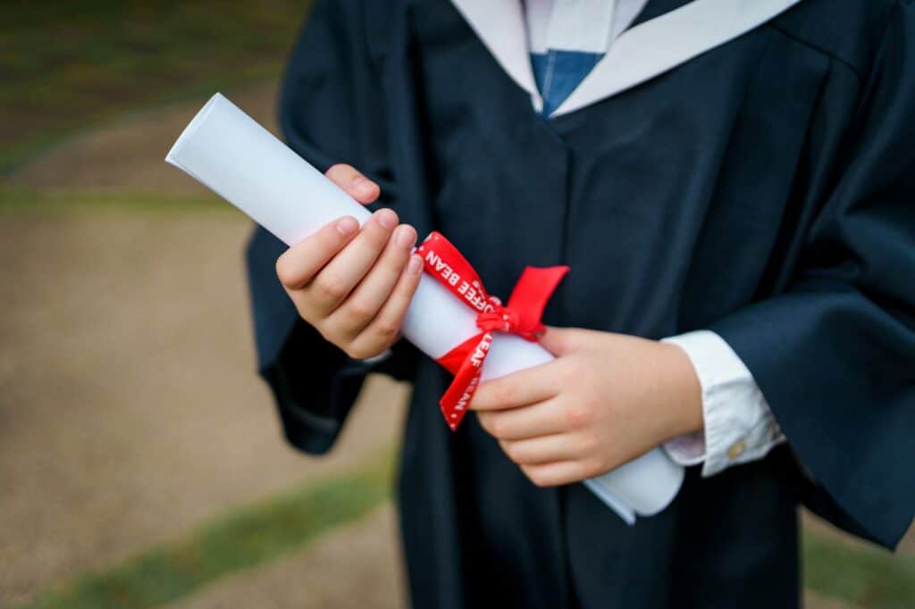 Kids on graduation gown holding graduation scroll